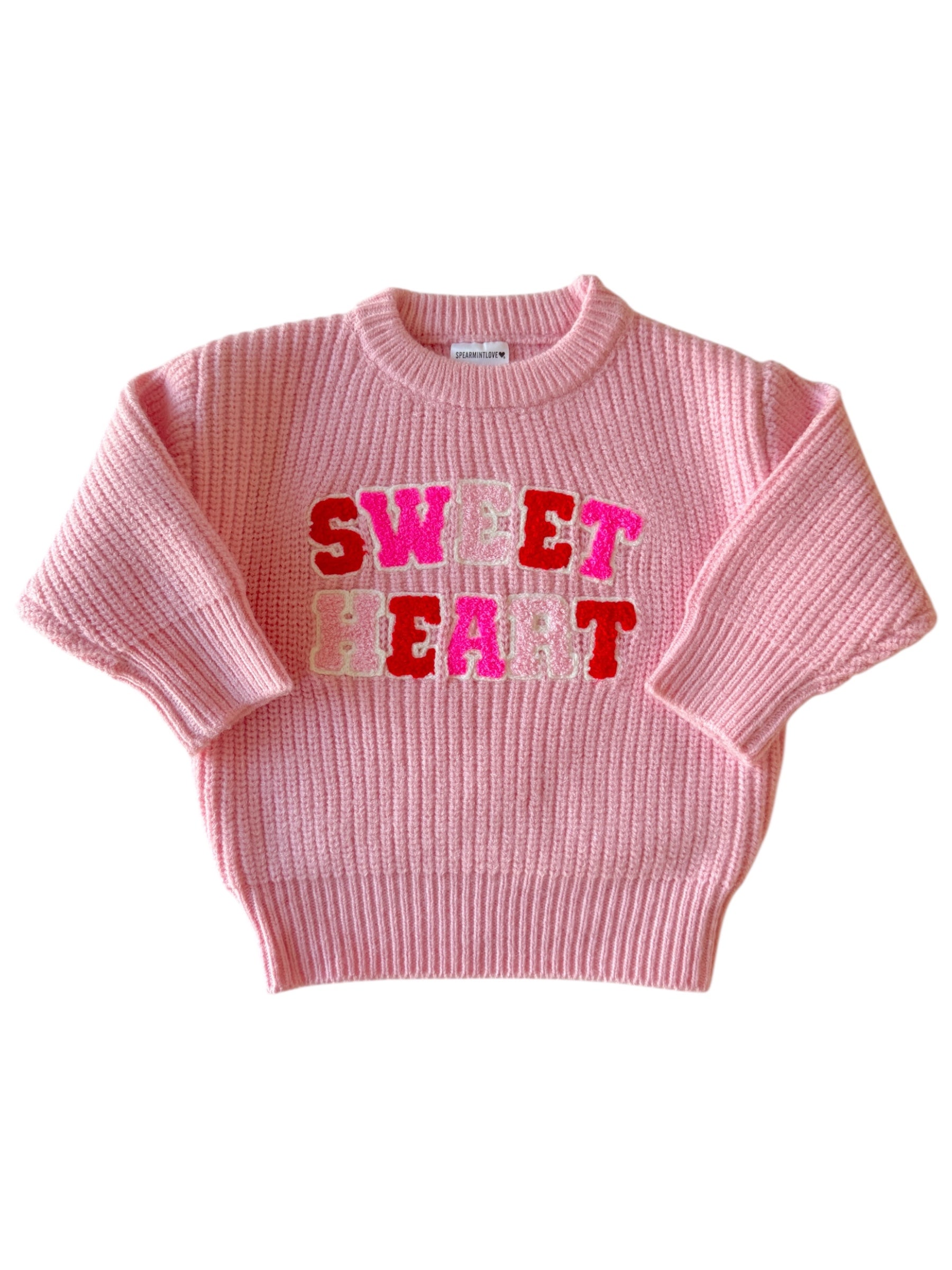 Pink knitted sweater featuring the words "SWEET HEART" in colorful lettering. Perfect for a stylish and cozy look.