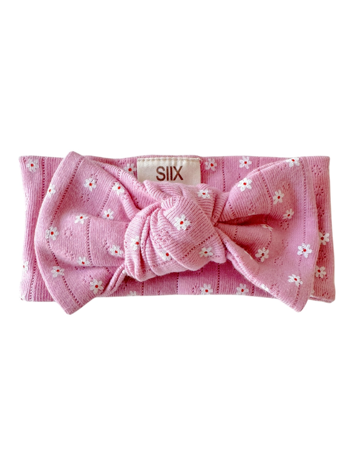 Pink headband with a knot detail and floral pattern, featuring a label that reads "SIIX."