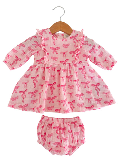 Pink dress with bow patterns and matching bloomers, displayed on a hanger against a white background.