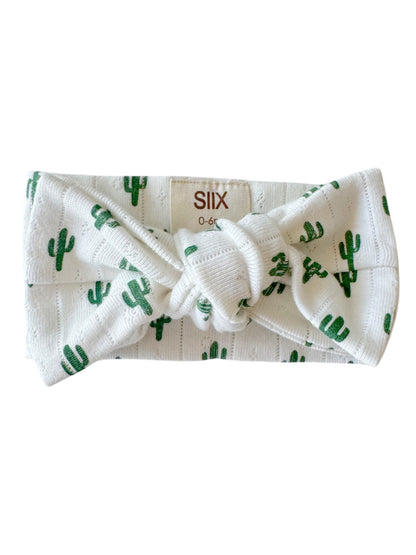 White headband with green cactus pattern, featuring a large knot in the center. Suitable for infants 0-6 months.