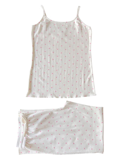 White pajama set with pink heart patterns, featuring a camisole top and matching pants laid flat.