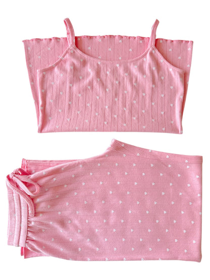 Pink pajama set featuring a spaghetti strap top and elastic waist bottoms, both with white heart patterns.