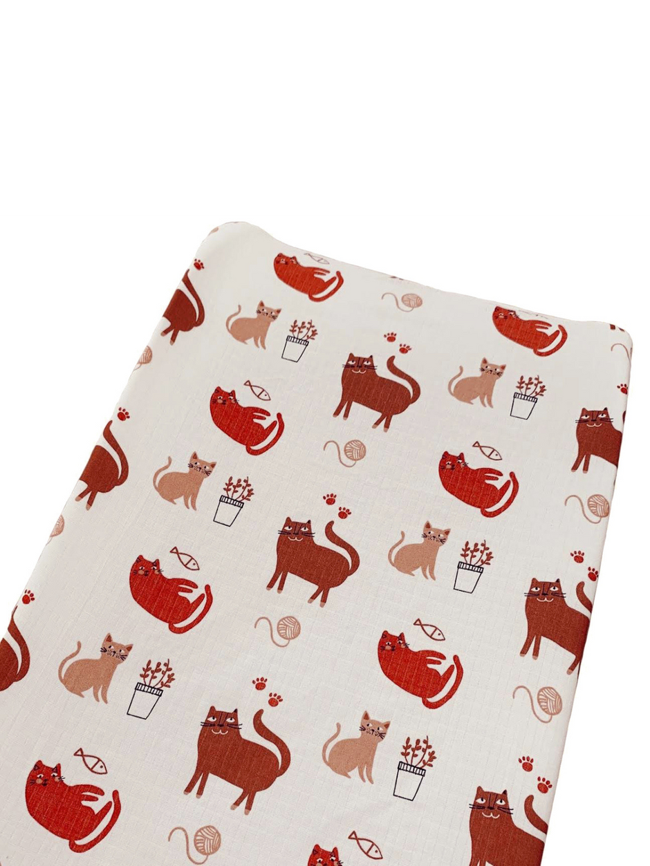 Patterned fabric featuring playful cats in various poses with plants and yarn.