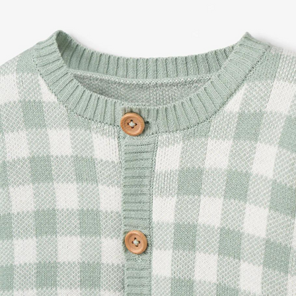 Green and white checkered sweater with a round neckline and wooden buttons.