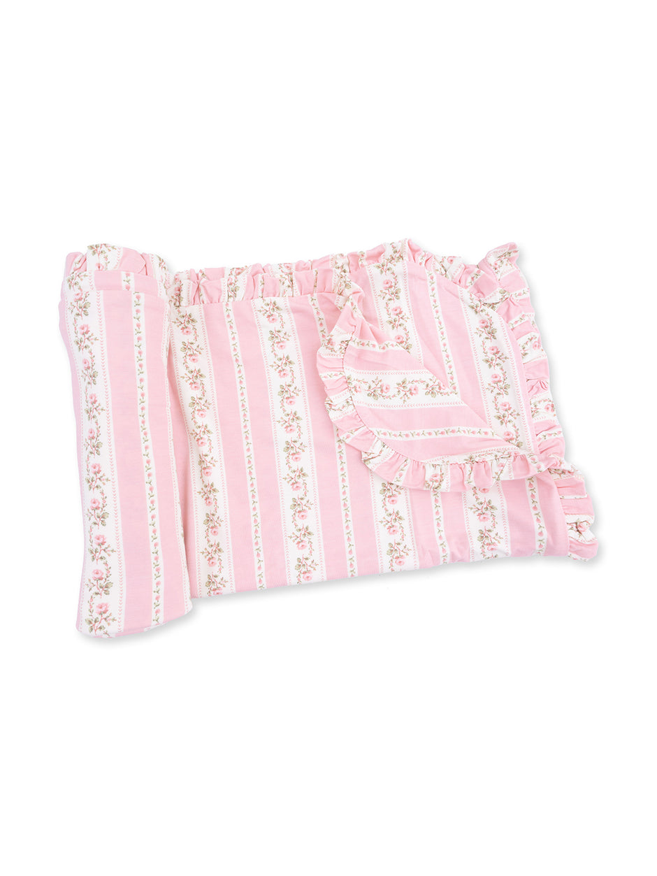 Pink striped bedding with floral patterns and ruffled edges, elegantly draped for a soft, cozy look.