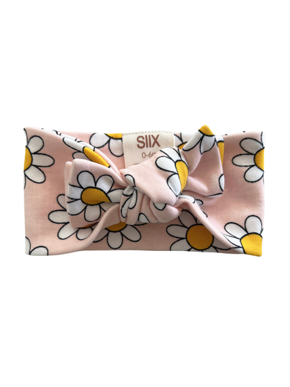 Pink flower headband with white daisies and yellow centers, featuring a front bow design. Ideal for infants 0-6 months.