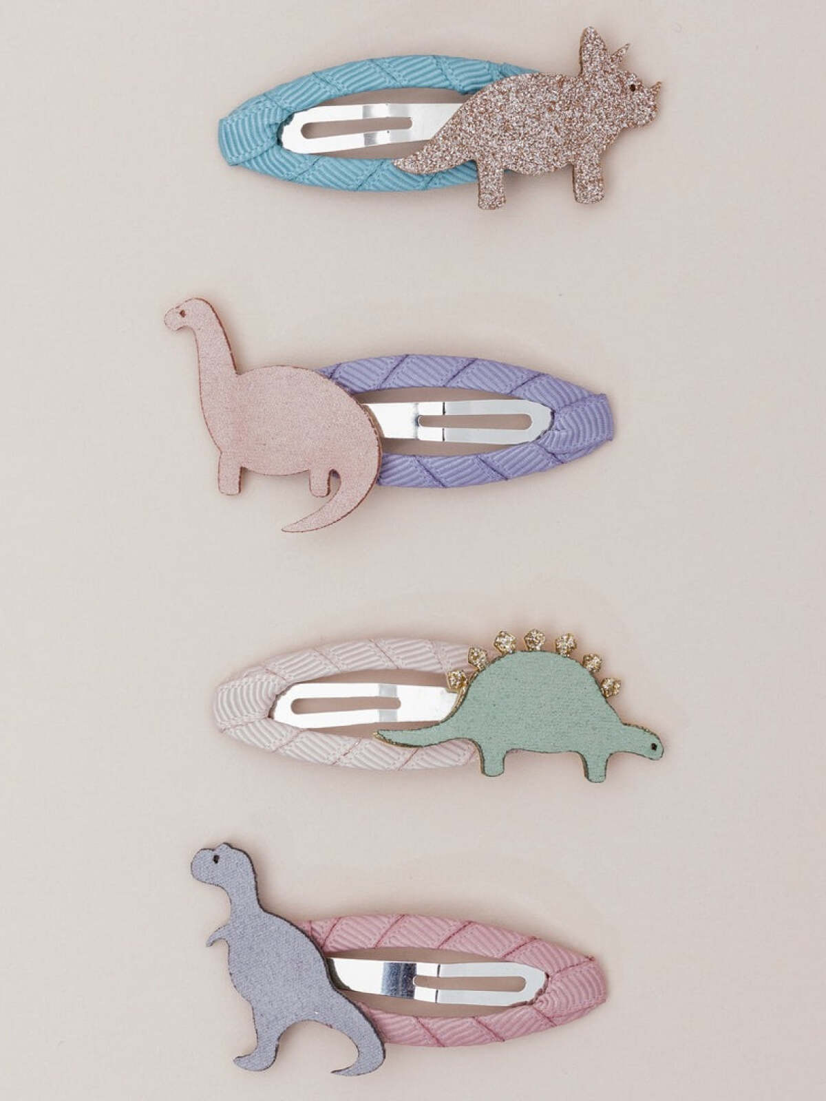 Four colorful hair clips featuring various dinosaur designs in soft pastel colors.