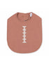 Pink baby bib with a football stitch design, featuring a snap closure at the neck. Ideal for mealtime.