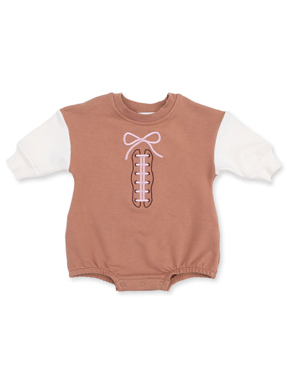 Brown baby onesie with white sleeves and a pink bow design resembling shoelaces.