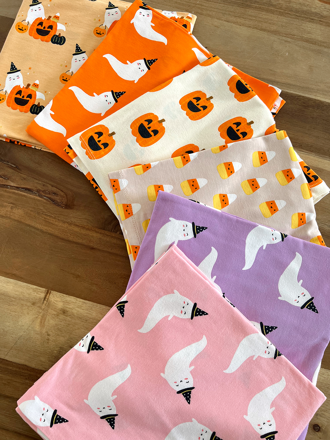 Colorful Halloween-themed fabrics featuring pumpkins, candy corn, and playful ghosts in various patterns.