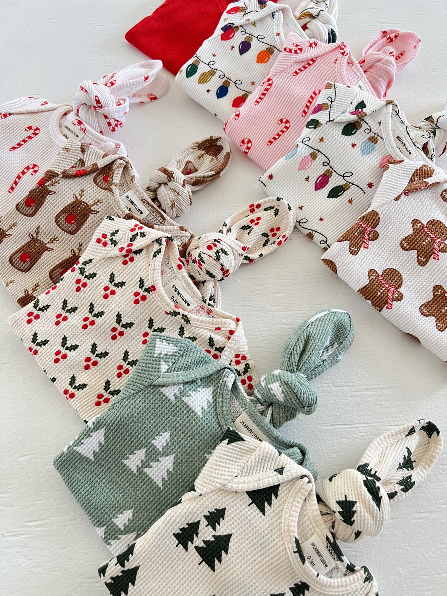 Colorful baby outfits displayed, featuring holiday patterns like candy canes and Christmas trees.