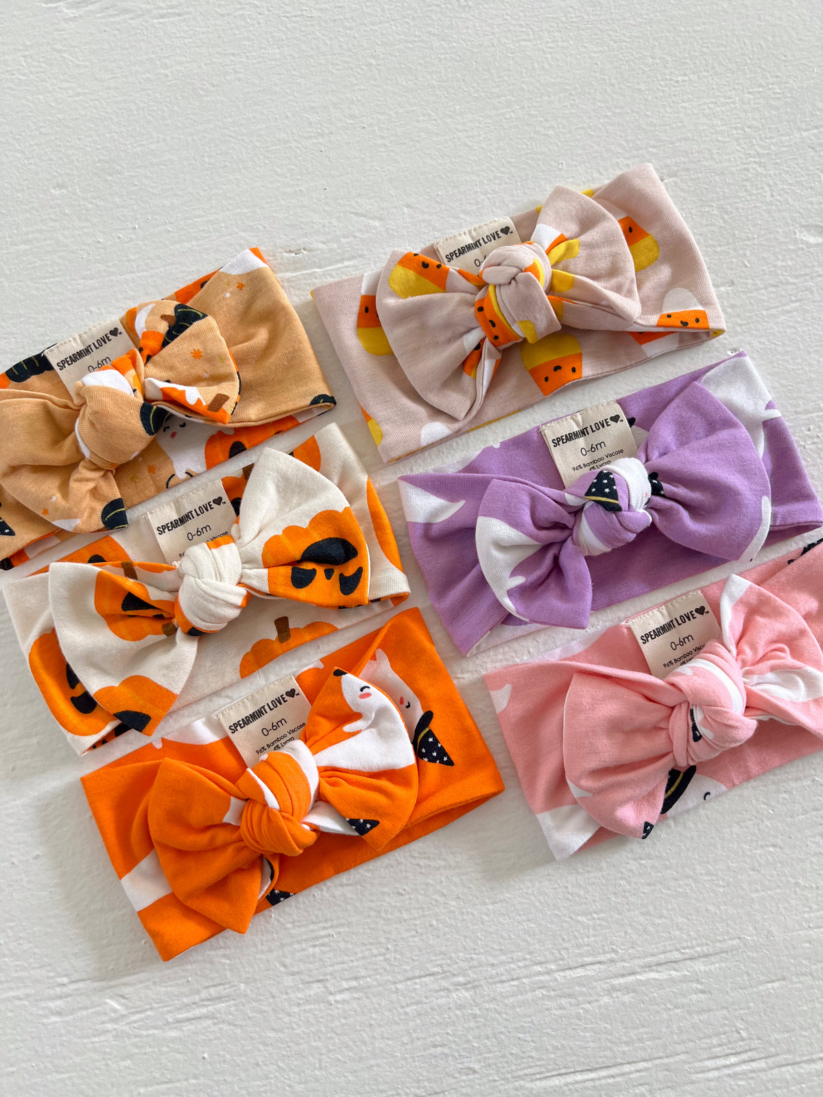 Six colorful baby headbands with bows in various patterns on a white background.
