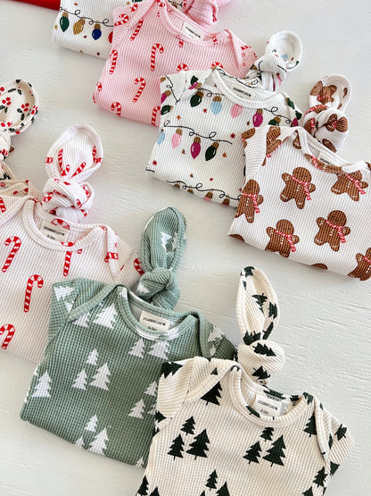 Colorful baby outfits with festive patterns including candy canes, Christmas lights, gingerbread, and trees.