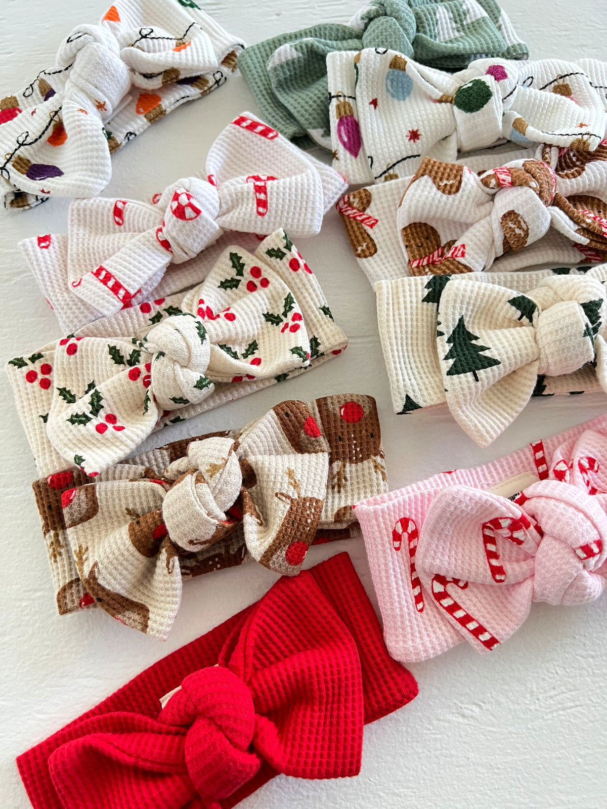 Collection of colorful fabric hair bows with holiday-themed patterns on a white background.