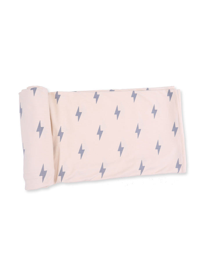 Light pink blanket rolled up with gray lightning bolt pattern, ideal for cozying up in style.