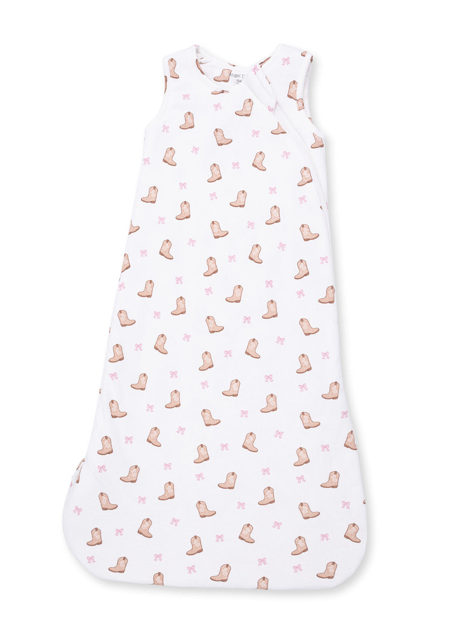 White baby sleep sack with a pattern of brown boots and pink bows. Soft and cozy for infants.