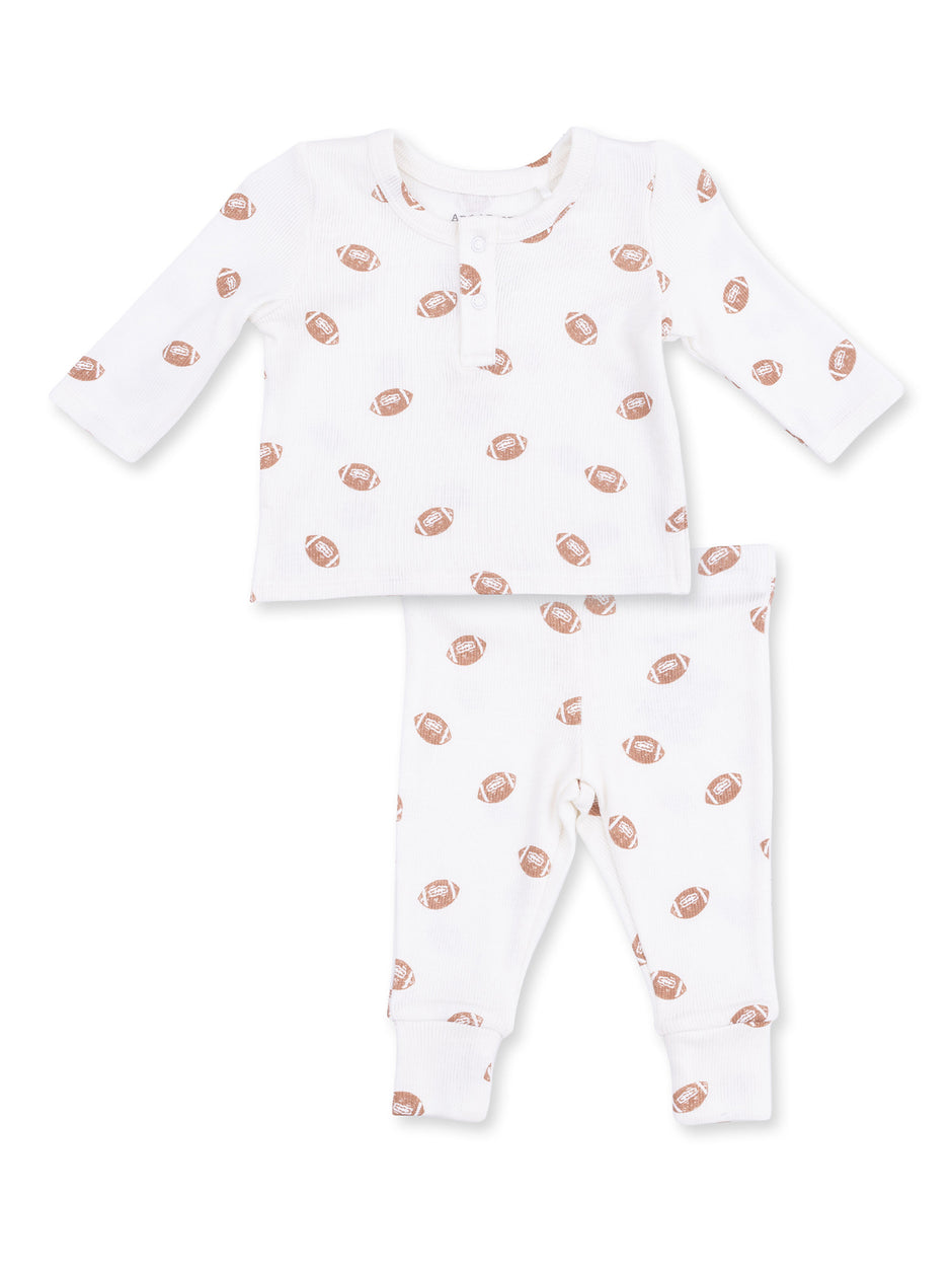 White baby outfit featuring a long-sleeve top and pants with a football print.