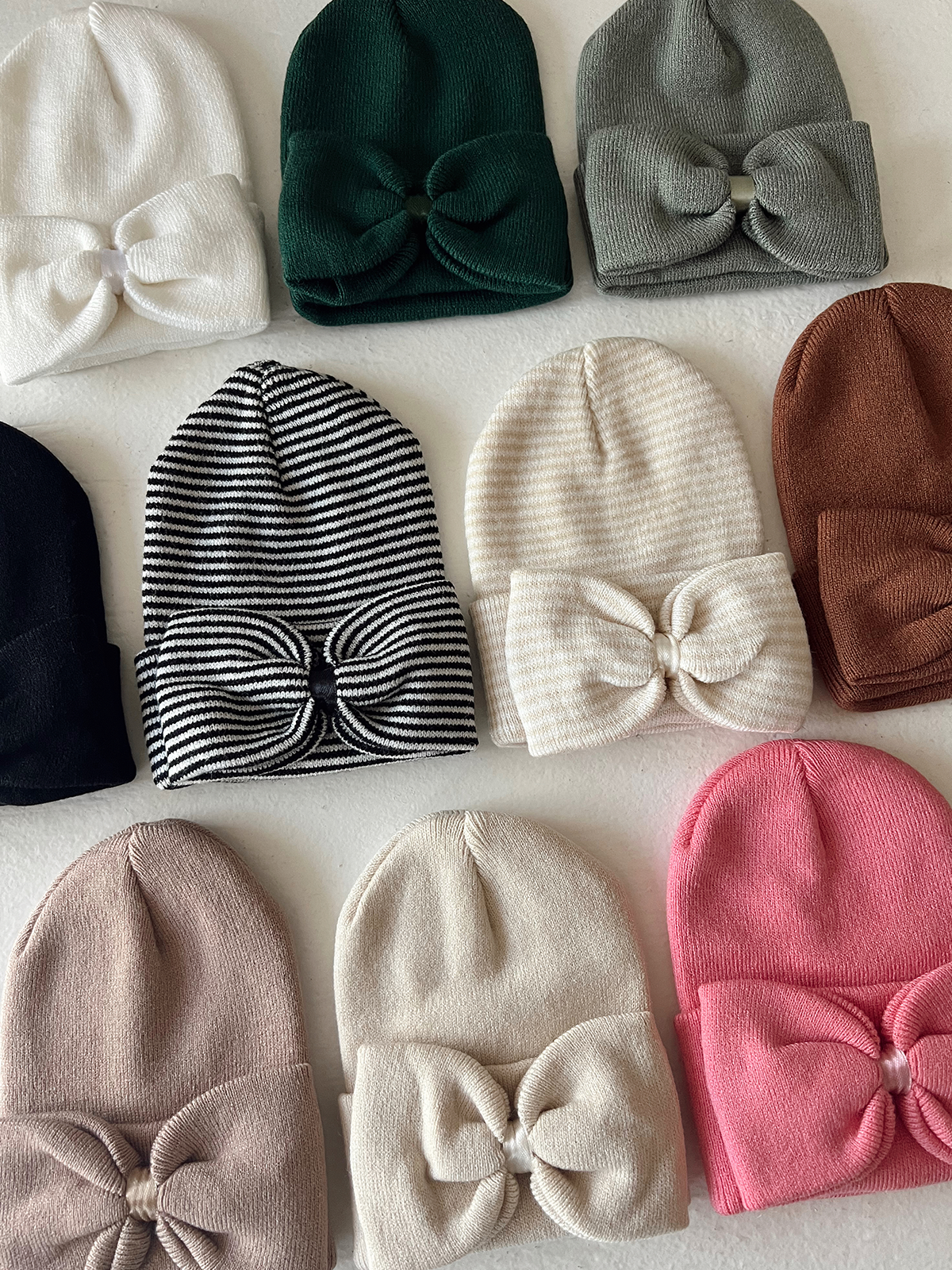 A variety of stylish beanies in different colors and designs, featuring bow details.