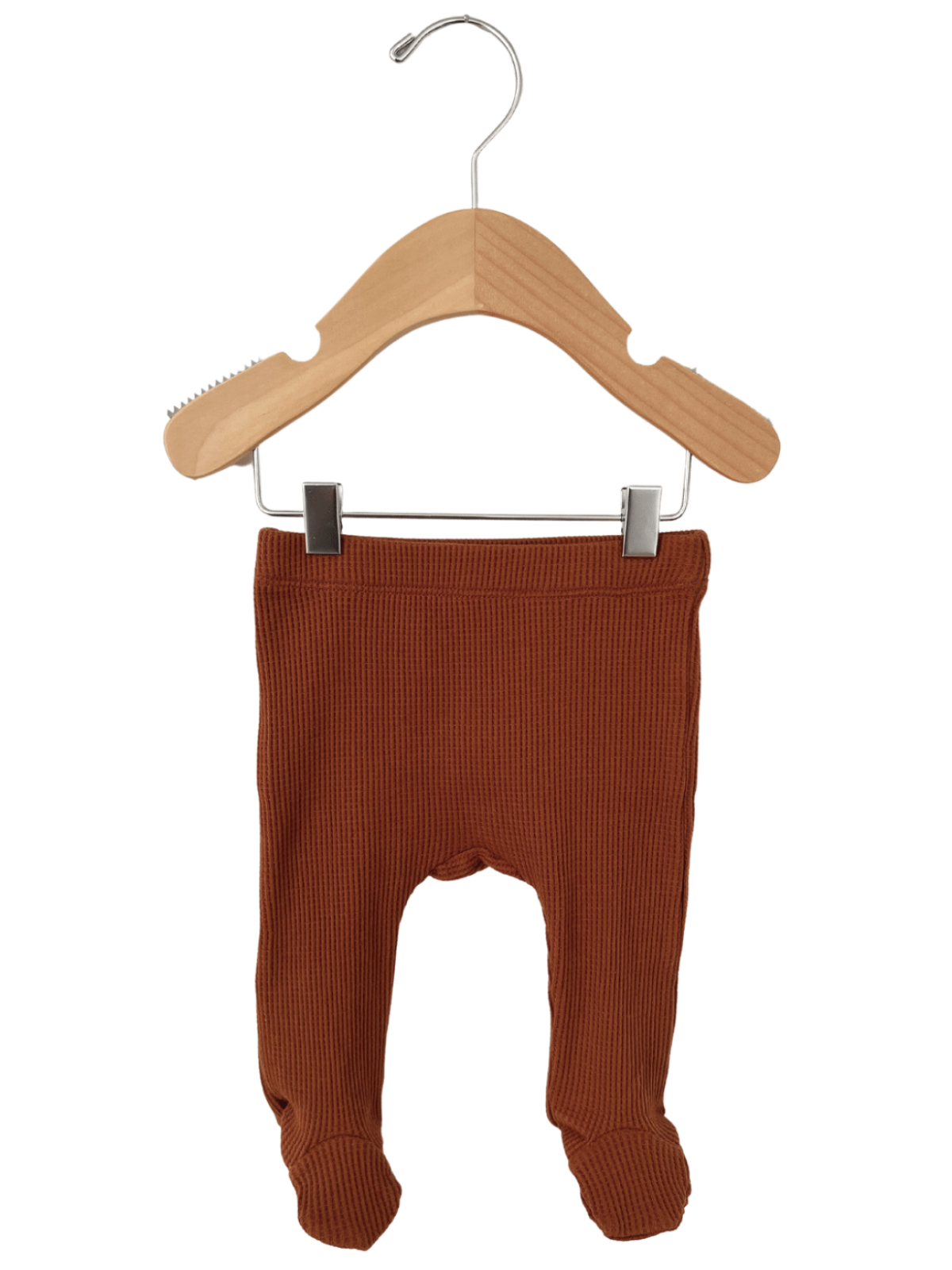 Rust-colored baby leggings hanging on a wooden hanger, showcasing ribbed texture and footed design.