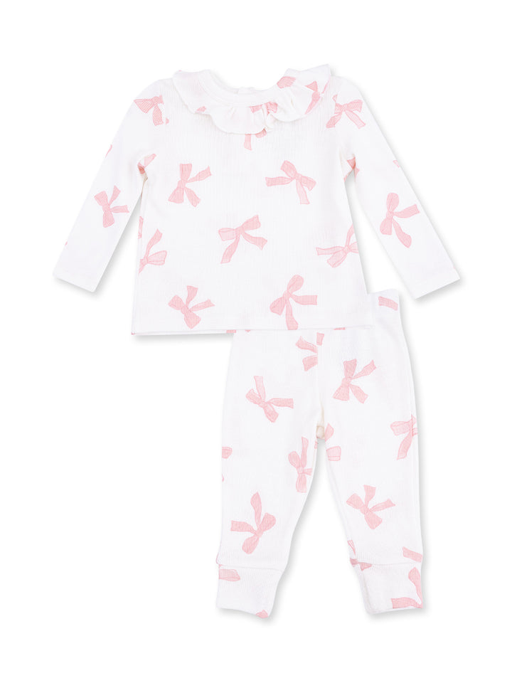 White pajama set featuring pink bow prints, long sleeves, and ruffled neckline. Ideal for toddlers.
