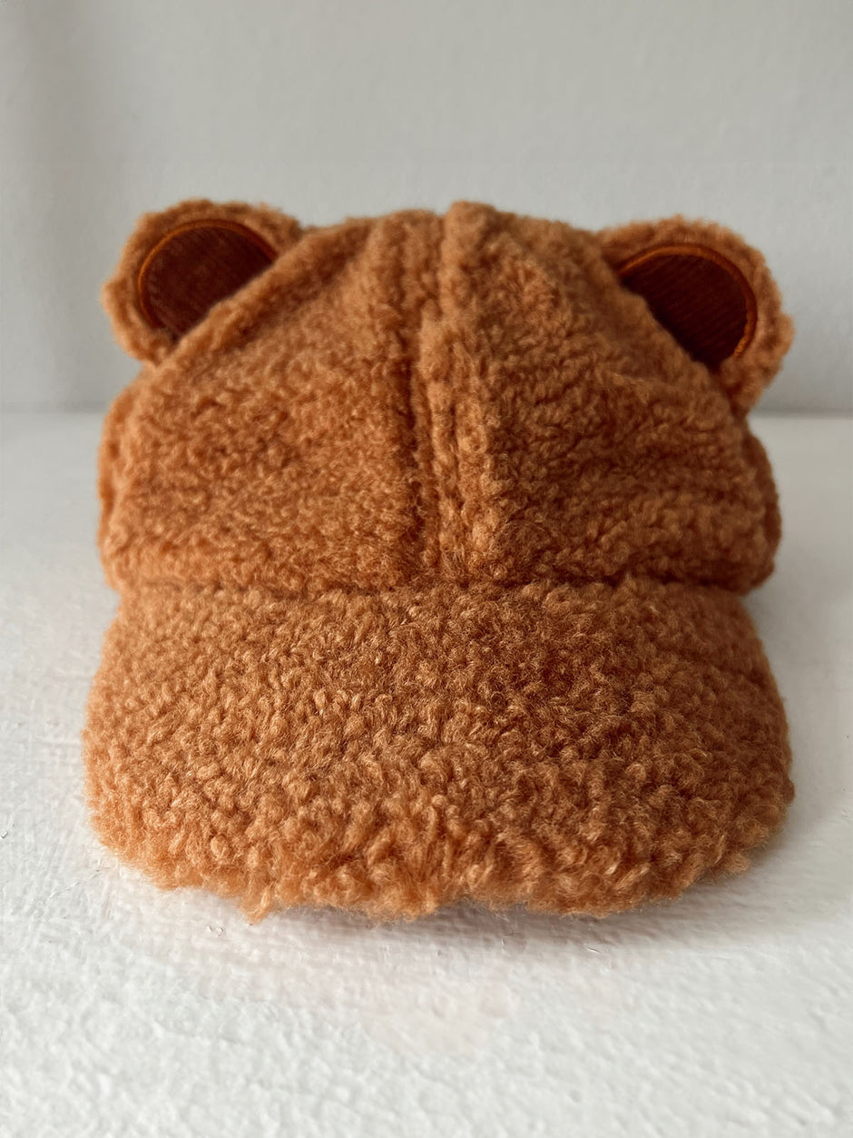 Brown bear-themed cap with fuzzy texture and ears, displayed against a white background.