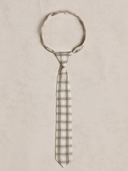 Gray and cream checkered tie laid flat on a light textured background.