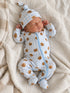 Newborn sleeping peacefully in a blue checkered onesie with bear prints and a matching hat on a cozy blanket.