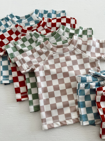 Colorful checkered kids' shirts and shorts stacked together on a white surface.