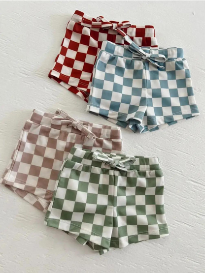 Checkerboard shorts in four colors: red, light blue, pink, and green, each with a matching bow.