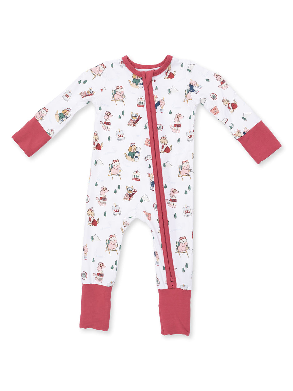 White children's onesie featuring colorful ski-themed illustrations and red accents on sleeves and feet.