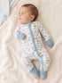 Baby smiling in a football-themed onesie, lying on a soft blanket.