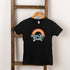 Black t-shirt hanging on a wooden ladder, featuring a colorful rainbow graphic and the text "Better than Great."