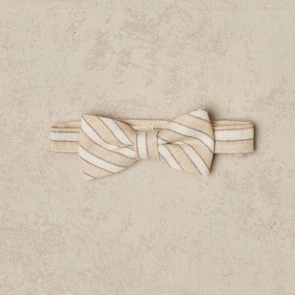 Beige and cream striped bow tie on a beige background. Classic accessory for formal occasions.