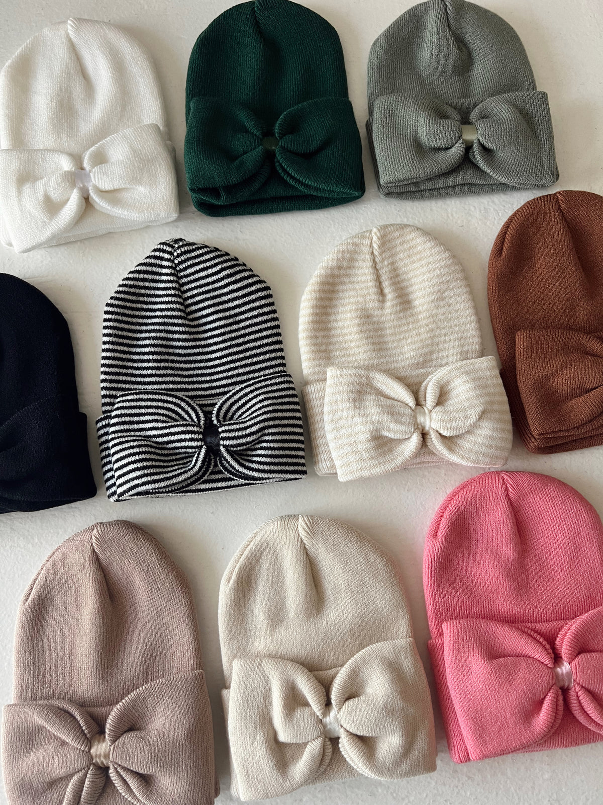 Collection of soft, stylish beanies in various colors with bow accents on a light background.