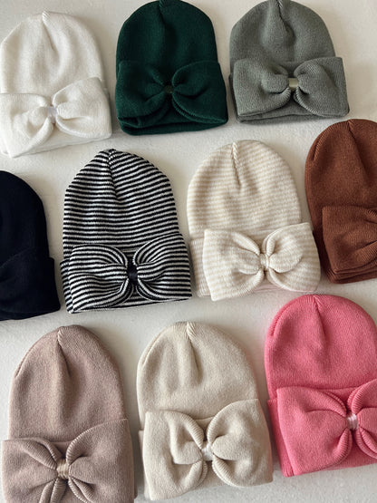 Collection of soft, stylish beanies in various colors with bow accents on a light background.